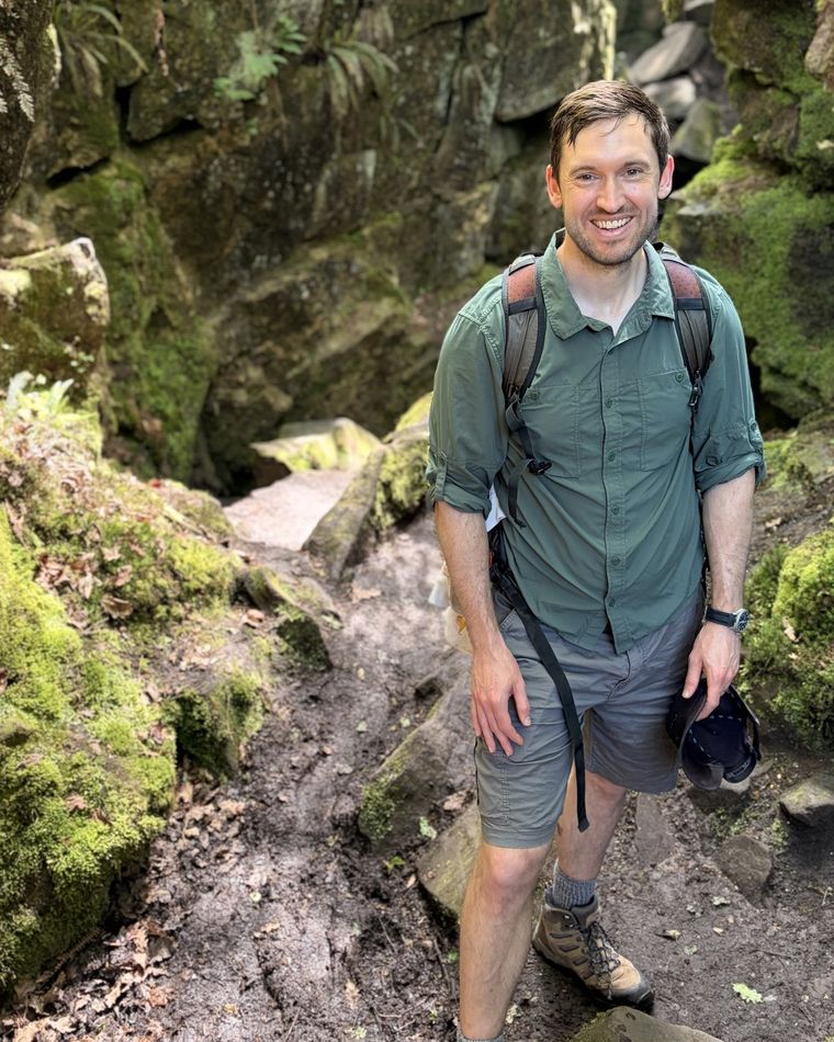 Dr Daniel O'Rourke on a rocky woodland path, in walking clothes with a rucksack