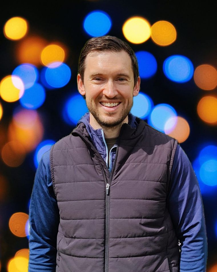 Portrait of Dr Daniel O'Rourke against a background of blurred orange and blue lights